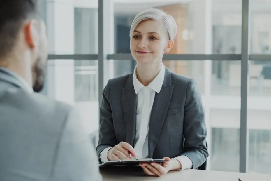 Vrouw in pak interviewt man aan tafel bij recruiter gesprek