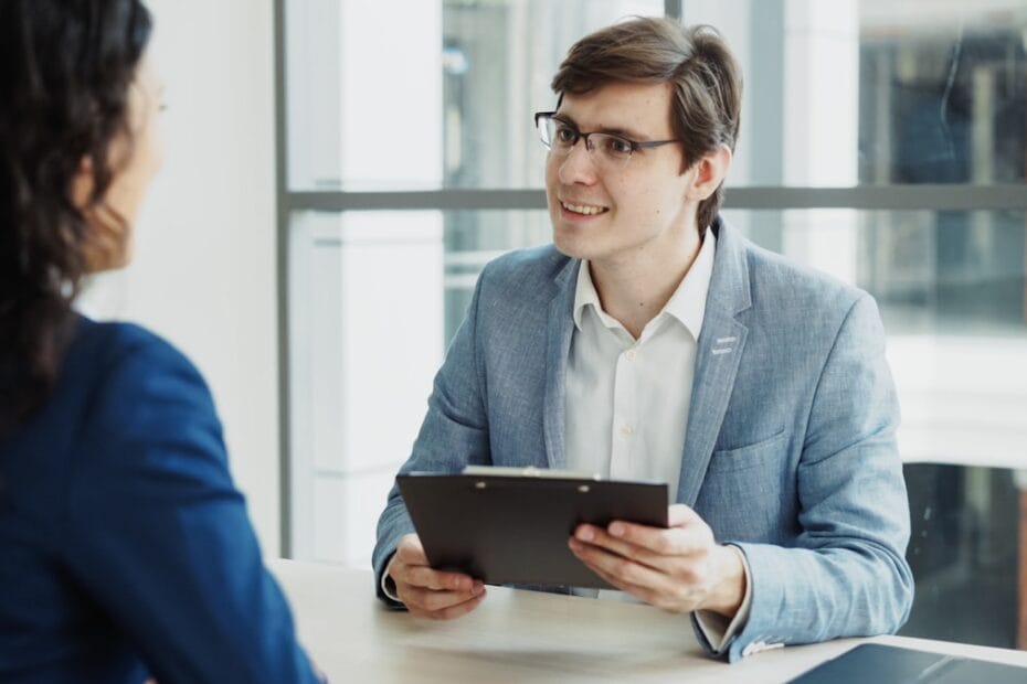 Recruiter in pak interviewt kandidaat met klembord tijdens sollicitatiegesprek