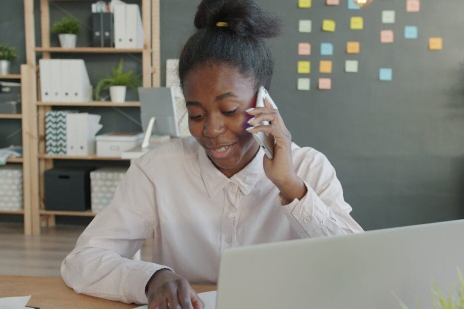 Jonge vrouw belt aan bureautelefoon met laptop voor mobiel recruitment