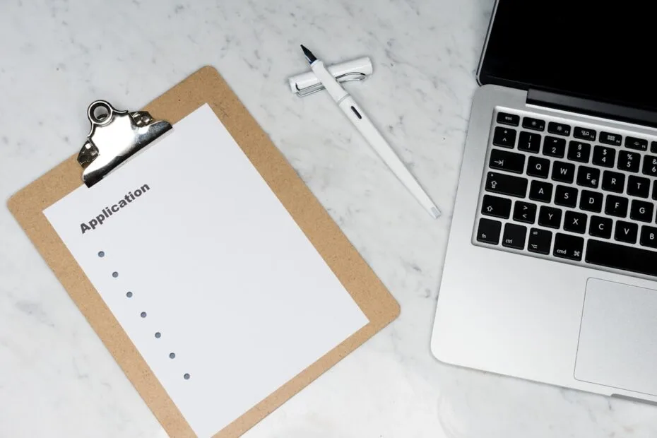 Papieren cv in map naast laptop klaar voor sollicitatieprocedure