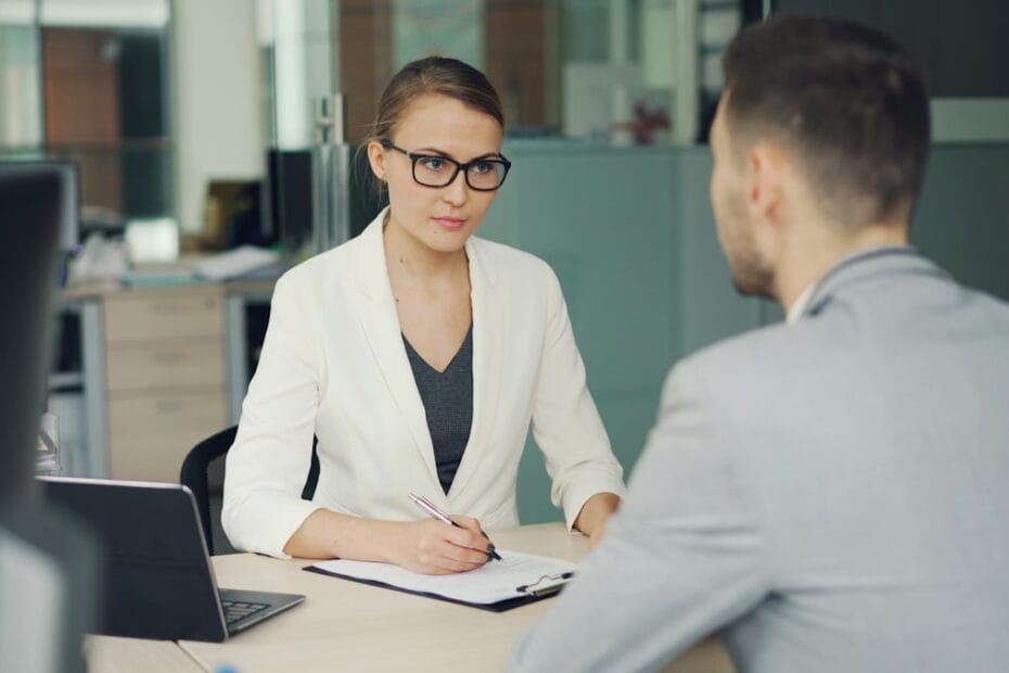 Vrouw interviewt man aan bureau op kantoor voor een sollicitatiegesprek