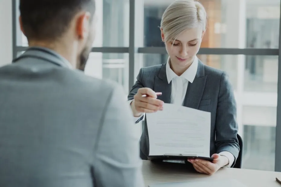 Vrouw in pak laat document zien aan man bij recruitment gesprek